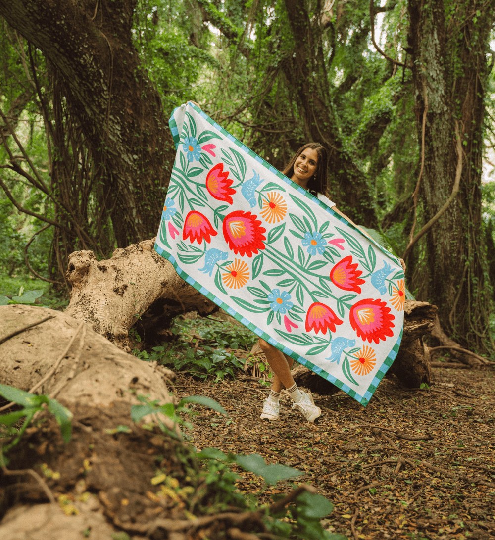 Vrouw houdt een Buvanha reishanddoek met bloemenprint open in een bos Vrouw houdt een Buvanha reishanddoek met bloemenprint open in een bos